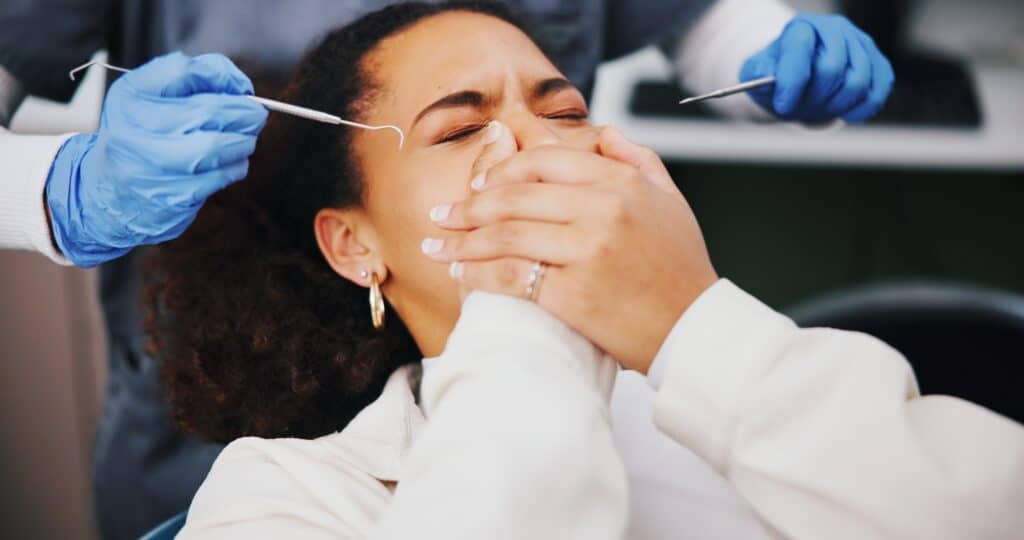 scared female dental patient, covering her mouth with hands