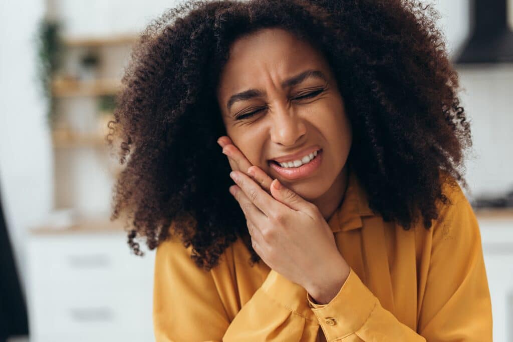 young woman holding her jaw with tooth pain