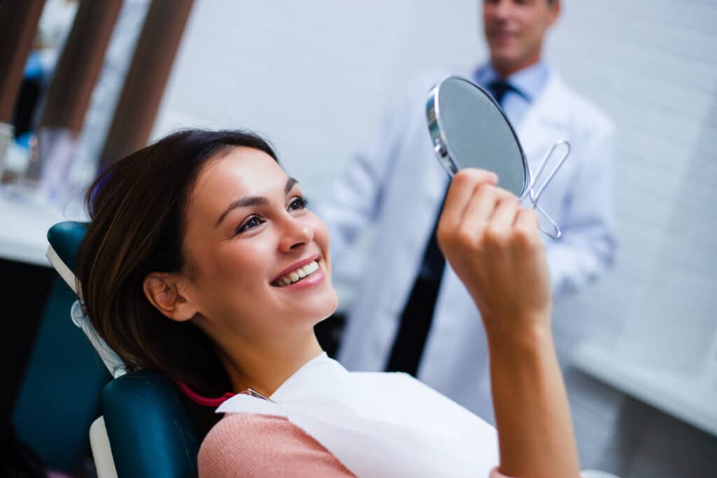 young woman smiling in dental chair, satisfied with her new smile