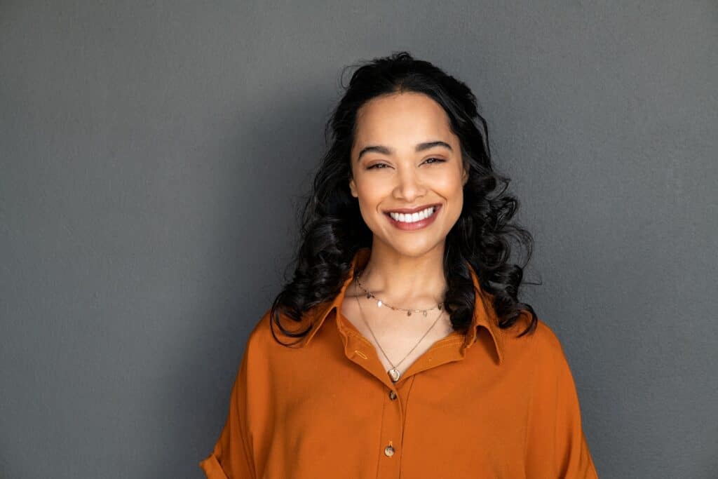 smiling young woman against a grey background, perfect veneers