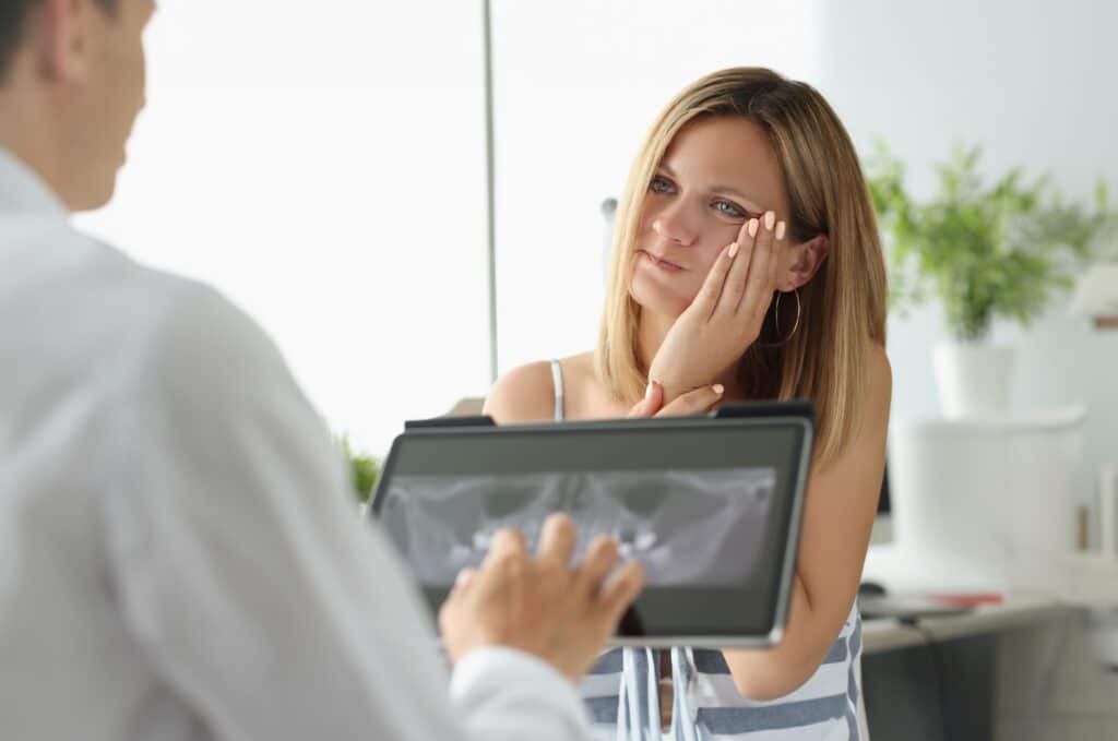 Female patient with acute toothache at doctor appointment with X-ray image