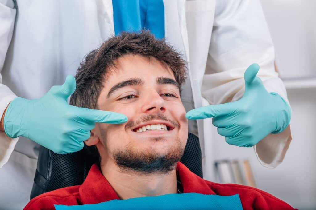 dentist in blue gloves showing off a mans restored smile, dental bridge